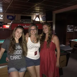 a group of friends posing for a picture in front of a pool table