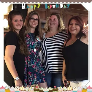 a group of women standing in front of a cake