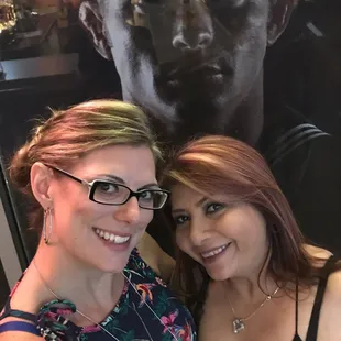 two women posing for a picture in front of a movie poster