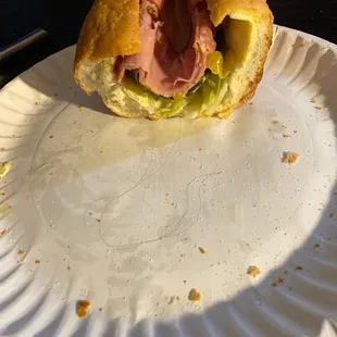 a half eaten sandwich on a paper plate