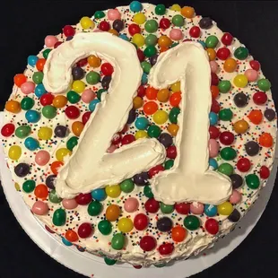 a birthday cake with white frosting and multicolored candies