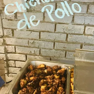 a pan of chicken wings in front of a brick wall