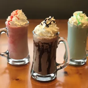 three glasses of milkshakes on a table