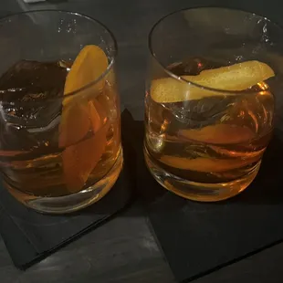 two glasses of whiskey with orange peels