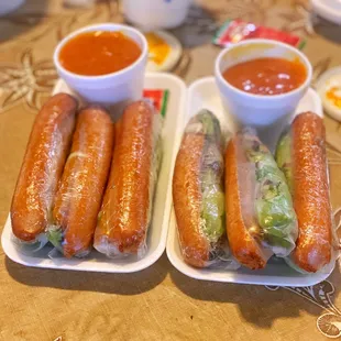 two trays of hot dogs and a bowl of ketchup