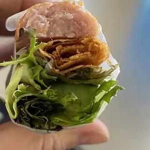 a person holding a sandwich with meat and lettuce