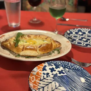 Adjarulu khachapuri and wine with cute appetizer plates