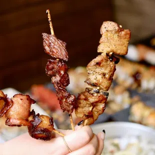a person holding a skewer of food