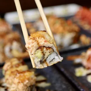 a close up of a sushi being held by a pair of chopsticks