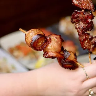 a person holding a skewer of food