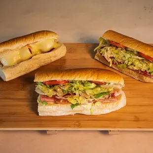 two sub sandwiches on a cutting board