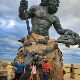 three people standing in front of a statue