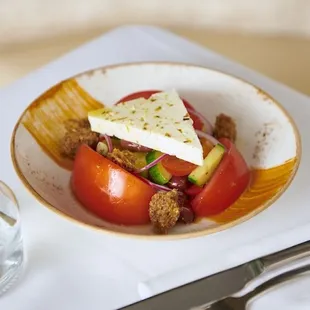 Traditional greek tomato salad served with feta, cucumber, onions, olives and tomato butter