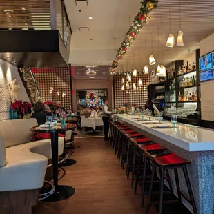 a restaurant with a long bar with red stools