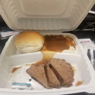 Tri tip with mashed potatoes and gravy and dinner roll.