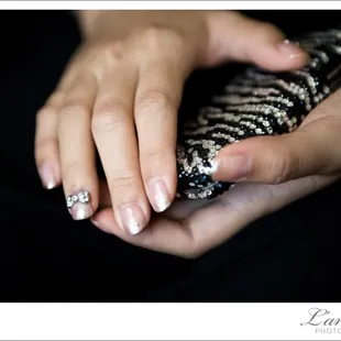 Dainty details:  a crystal bow on the bride&apos;s ring finger looks dazzling against her case.  Photo by L&apos;amour Photography.
