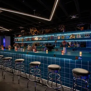 a bar with stools and neon lights
