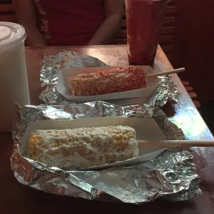 Corn on a cob one with just mayo and cheese and the other one with mayo, cheese and chili powder