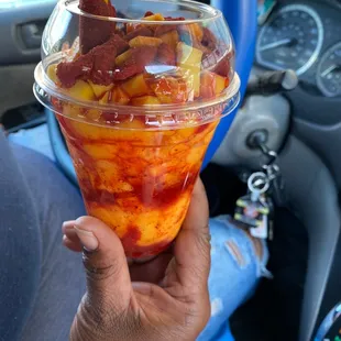 a hand holding a cup of fruit