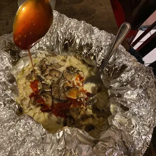 a spoon drizzing sauce over a pizza