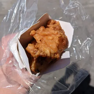 a hand holding a piece of fried chicken