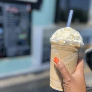 a hand holding a cup of iced coffee