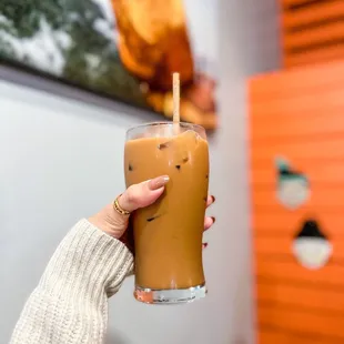 a hand holding a glass of iced coffee