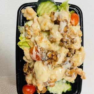 a black plastic container with a salad in it