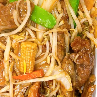 a plate of stir fried noodles with meat and vegetables