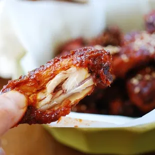 a hand holding a piece of chicken wings