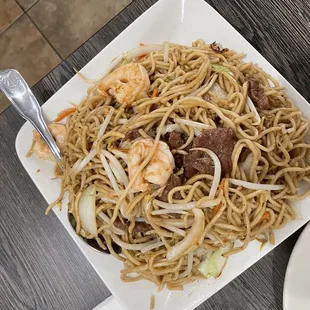 a plate of noodles with meat and shrimp