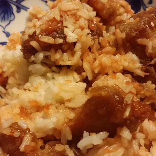 a plate of rice and meat with chopsticks
