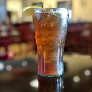 a glass of iced tea with a lemon wedge