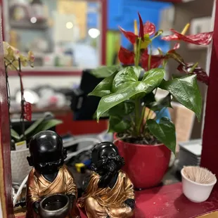 two figurines of buddhas and a potted plant