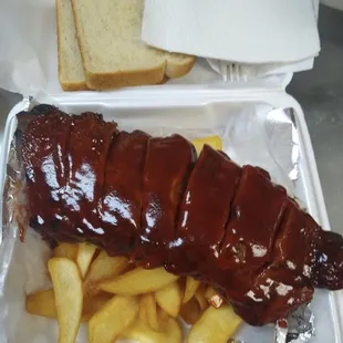 ribs and french fries in a styrofoam container
