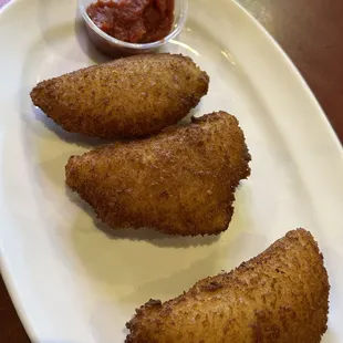 three fried fish fingers on a white plate