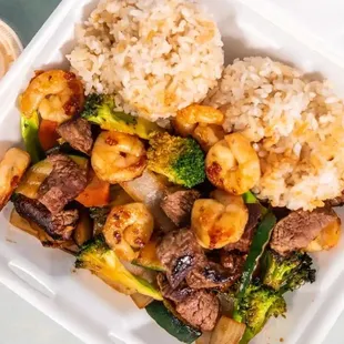 a takeout container with rice, broccoli, and meat