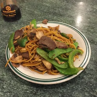 a plate of noodles with beef and snap peas