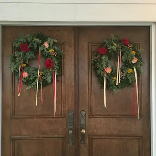Natural wreaths w/ individual blooms tucked in and ribbon streatmers set the tone before guests enter a wedding.