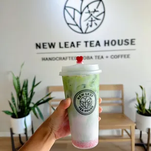 a hand holding a cup of green tea