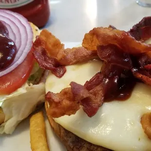 Bbq bacon cheeseburger on a toasted roll, lettuce and tomatoes,  fries on the side