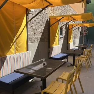 tables and chairs under yellow umbrellas