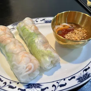 a plate of spring rolls and a bowl of dipping sauce