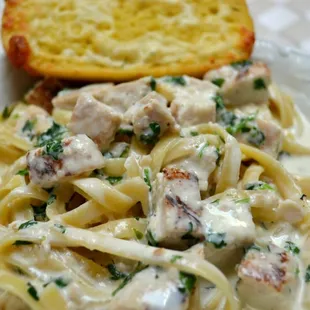Chicken Alfredo served over fettuccine pasta with garlic bread.