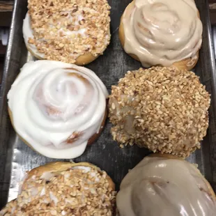 White and maple iced cinnamon rolls, some with granulated peanuts.