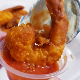 a hand holding a container of fried chicken
