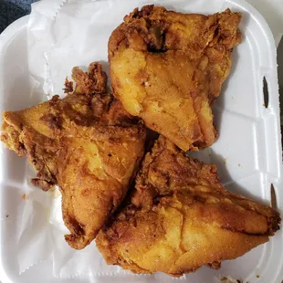 three pieces of fried chicken in a styrofoam container