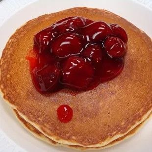 a stack of pancakes with cherries on top