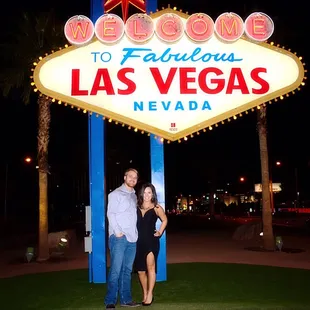 a couple standing in front of a welcome sign