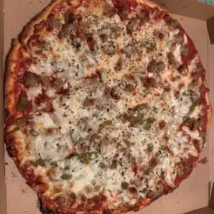 Sausage pizza with green peppers on half.